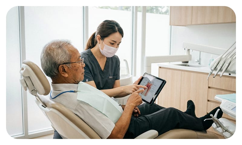 An elderly man receiving a professional dental consultation about his personalized implant treatment plan in a clinic setting.