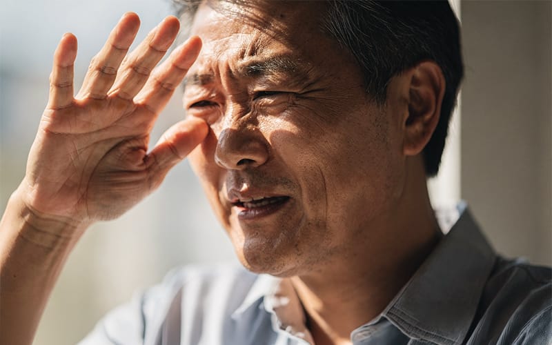An elderly patient experiencing glare and light sensitivity in a bright environment