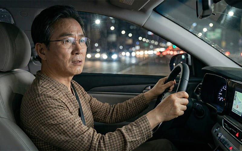 밤에 운전석에 앉아 걱정하고 있는 안경을 쓴 고령 환자