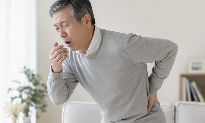 A person clutching their lower back while sneezing